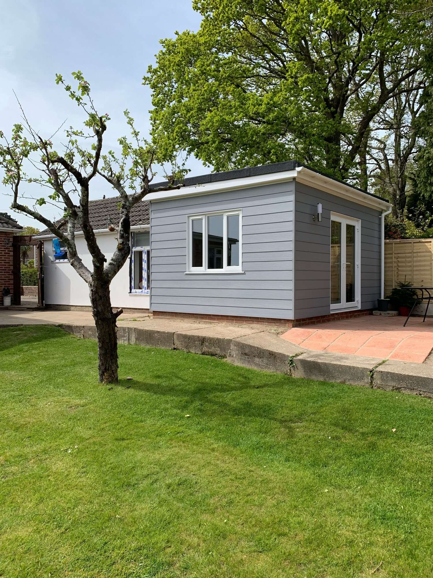 Single-storey extension with grey cladding, white French doors and a new patio