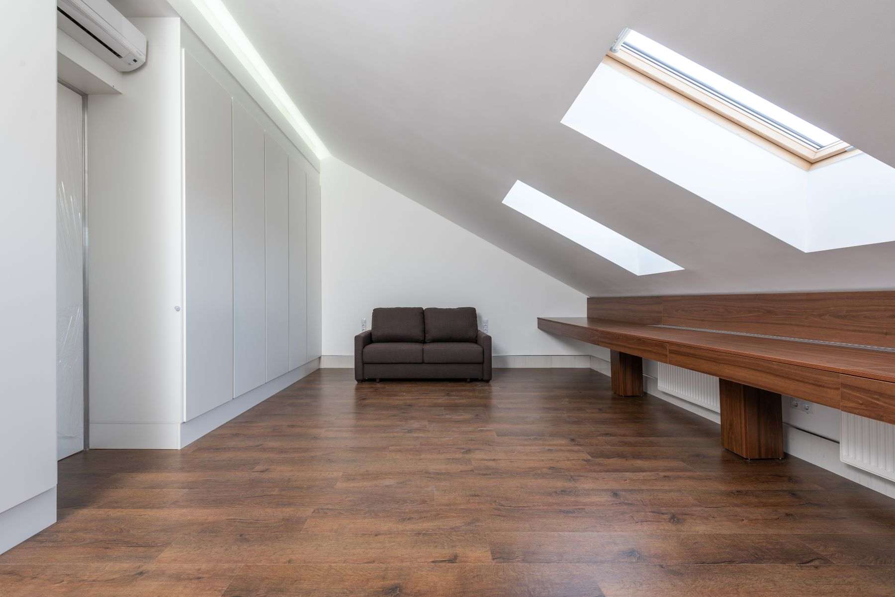 A finished loft room with roof windows in the sloping ceiling and a wooden floor