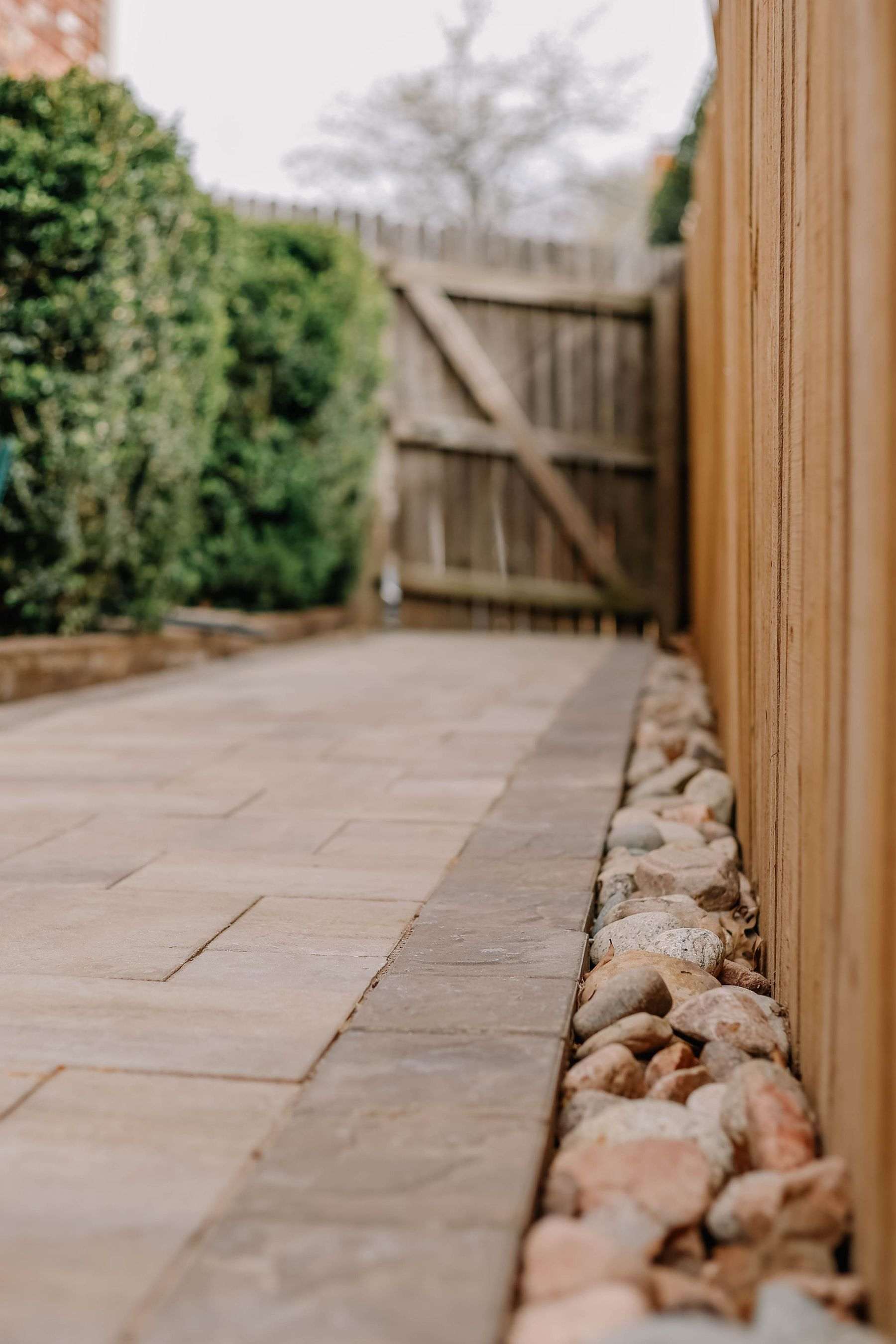 New paving slabs running beside a closeboard timber fence and a wooden side gate